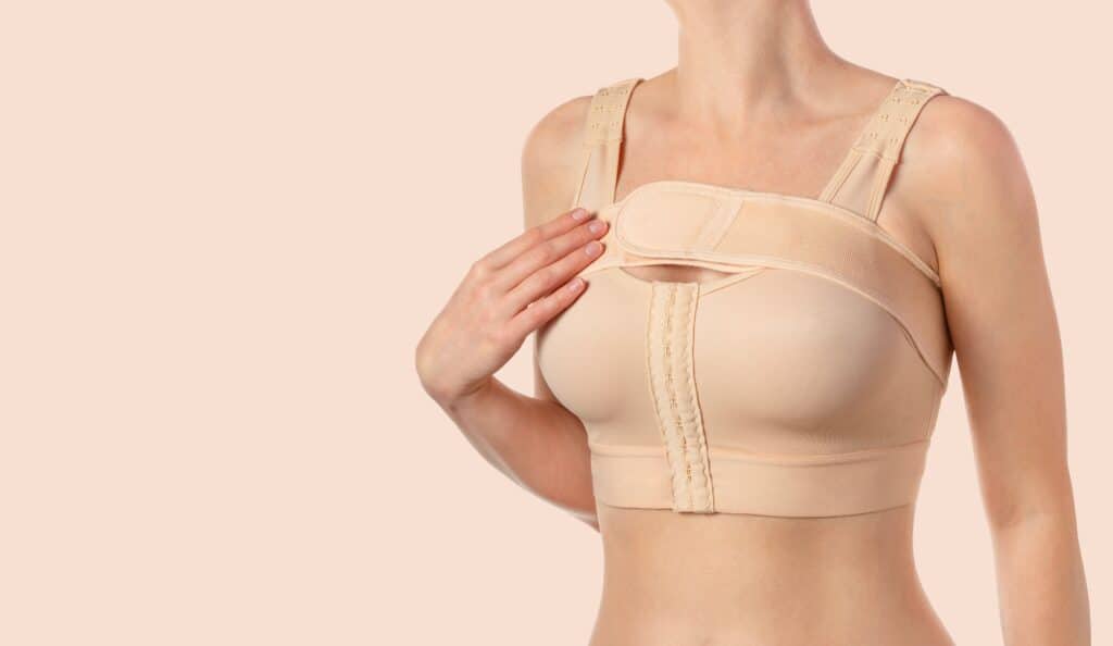 Woman wearing compression bra post breast enhancement surgery for mommy makeover