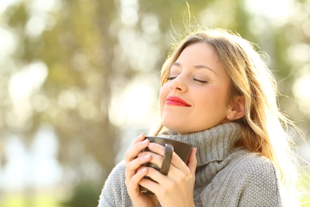 Woman outside breathing in fresh air and coffee after functional and cosmetic rhinoplasty